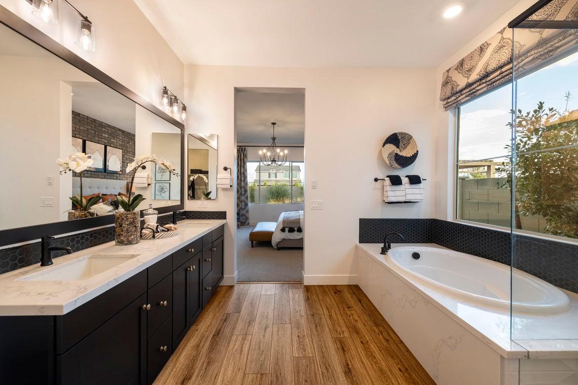 New home primary bathroom with wood flooring