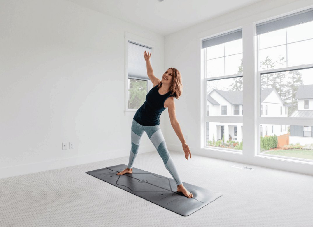 Woman doing yoga poses in home gym featuring natural lighting and yoga mat