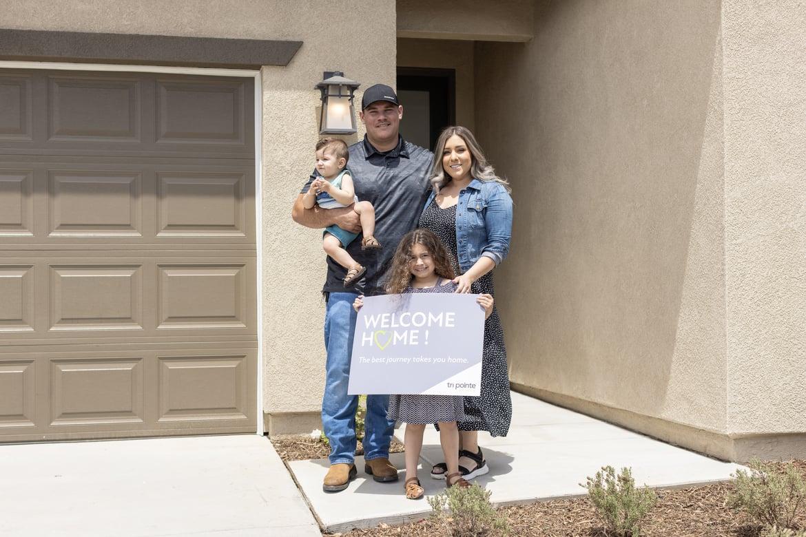 happy homeowners on moving day in front of their newly built home