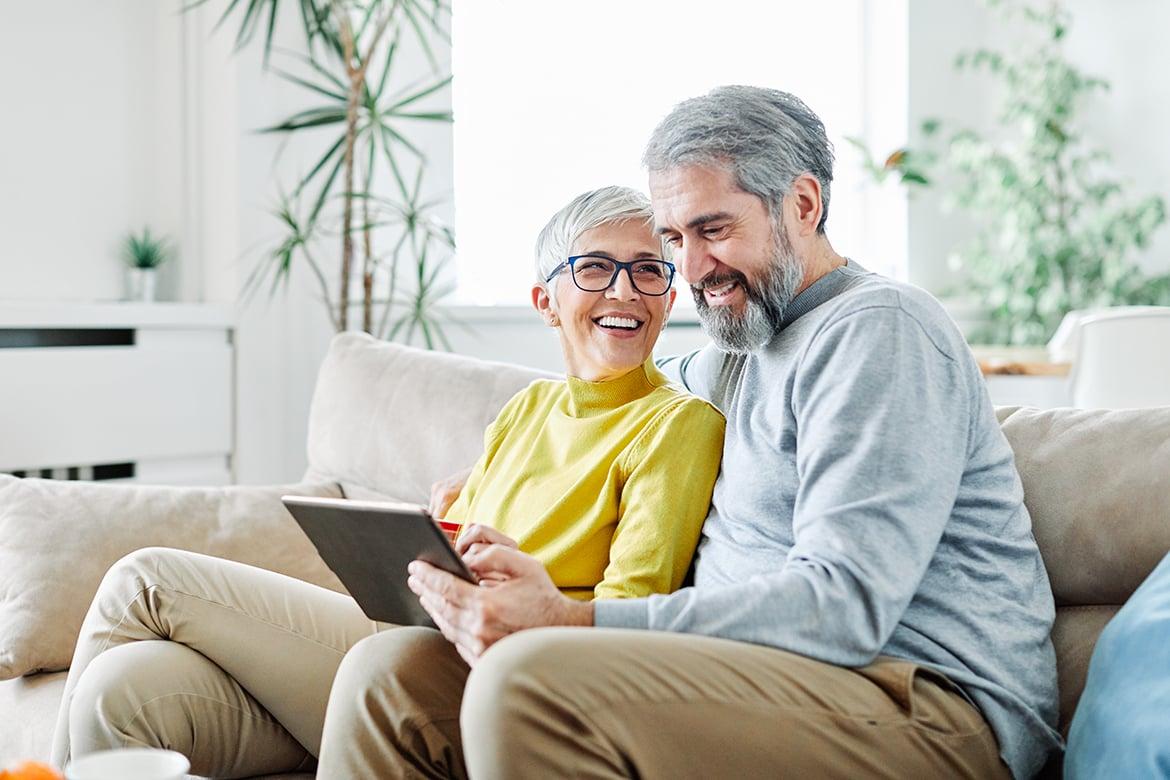 Portrait of happy smiling senior couple using tablet at home