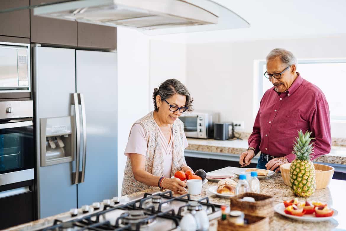 Elderly couple preparing breakfast in kitchen